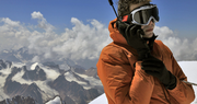 A man on a snowy mountain talking into a satellite phone