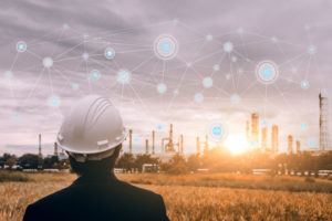 A worker looks towards a remote power plant that utilizes satellite-connected IoT to transmit real-time data.